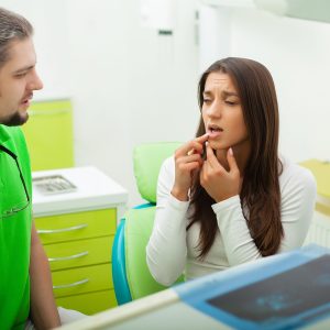 Dentist in dental office talking with female patient and preparing for treatment.